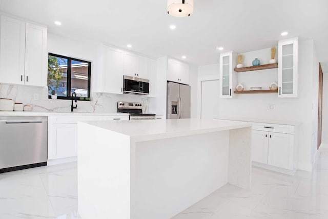 kitchen featuring appliances with stainless steel finishes, white cabinetry, a center island, and sink