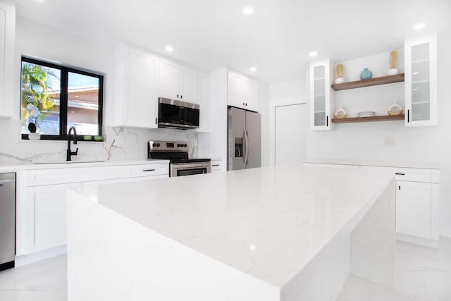 kitchen with appliances with stainless steel finishes, white cabinetry, and light stone countertops