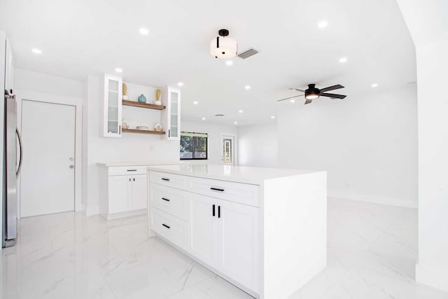 kitchen featuring ceiling fan, a kitchen island, and white cabinets