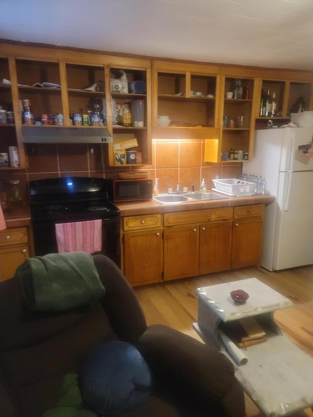 kitchen with black appliances, backsplash, sink, and light hardwood / wood-style floors