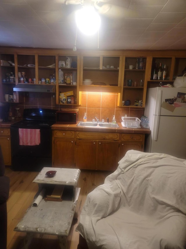 kitchen featuring range hood, light wood-type flooring, white refrigerator, sink, and black range with electric stovetop