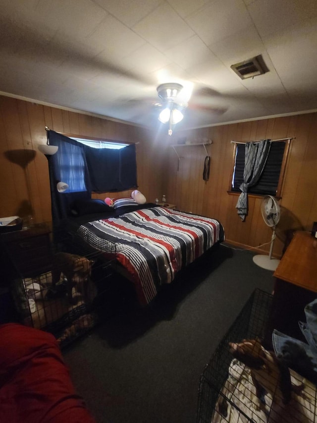 carpeted bedroom featuring wooden walls and ceiling fan