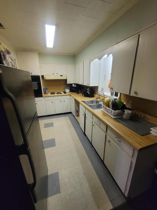 kitchen featuring sink, ornamental molding, white stovetop, white cabinetry, and black oven