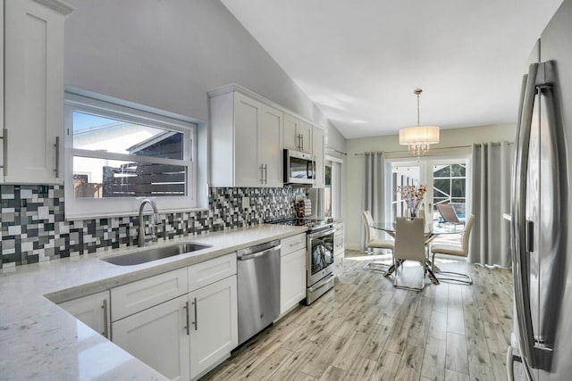 kitchen with stainless steel appliances, plenty of natural light, sink, and lofted ceiling