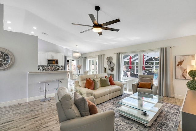 living room featuring ceiling fan, vaulted ceiling, and light hardwood / wood-style floors