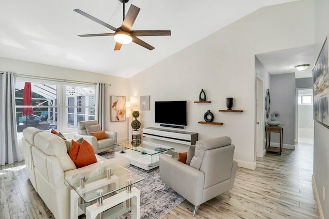 living room with ceiling fan, plenty of natural light, light wood-type flooring, and vaulted ceiling