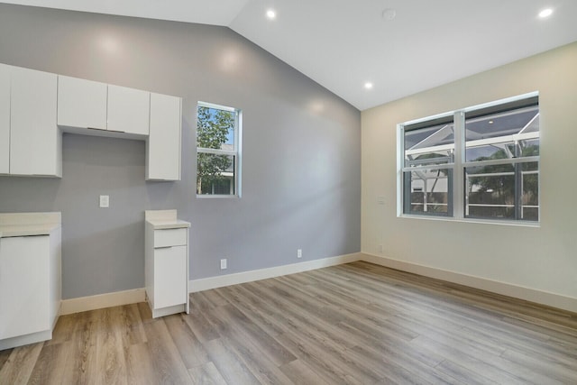 kitchen with white cabinetry, light wood-type flooring, and vaulted ceiling