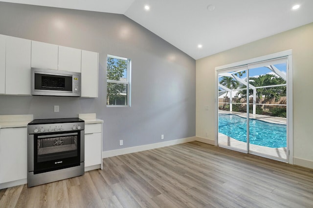 kitchen with white cabinetry, light wood-type flooring, appliances with stainless steel finishes, and vaulted ceiling