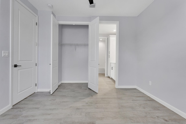 unfurnished bedroom with a closet, light hardwood / wood-style flooring, and ceiling fan