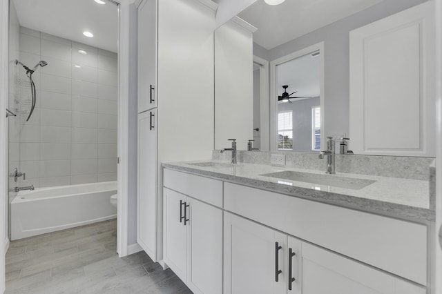 full bathroom featuring ceiling fan, vanity, toilet, and tiled shower / bath