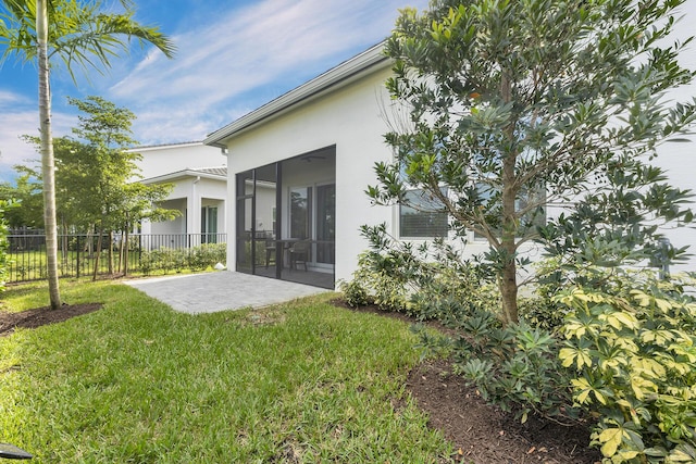 rear view of property featuring a sunroom, a lawn, and a patio