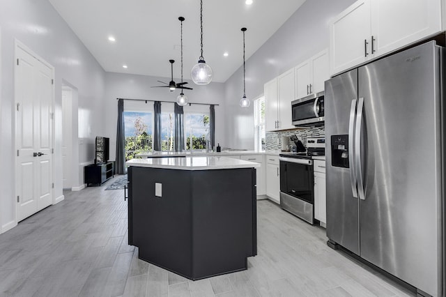 kitchen with backsplash, a center island, hanging light fixtures, appliances with stainless steel finishes, and white cabinets