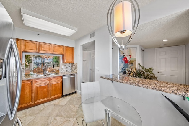 kitchen featuring light stone counters, backsplash, a textured ceiling, sink, and stainless steel appliances