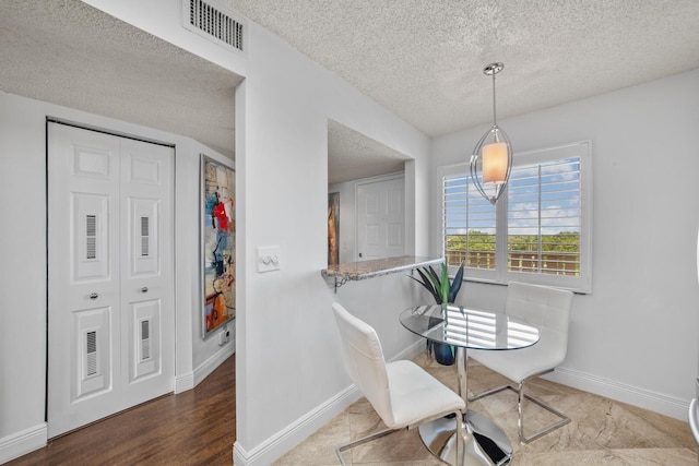 dining room with a textured ceiling and hardwood / wood-style floors