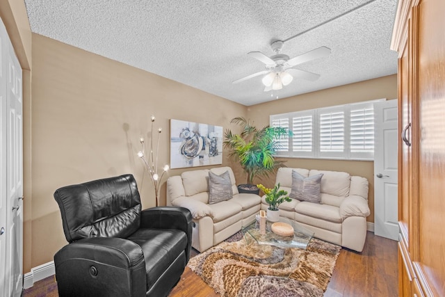 living room featuring dark wood-type flooring, ceiling fan, and a textured ceiling