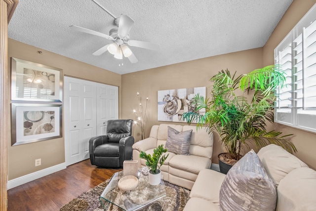 living room with a textured ceiling, dark wood-type flooring, and ceiling fan