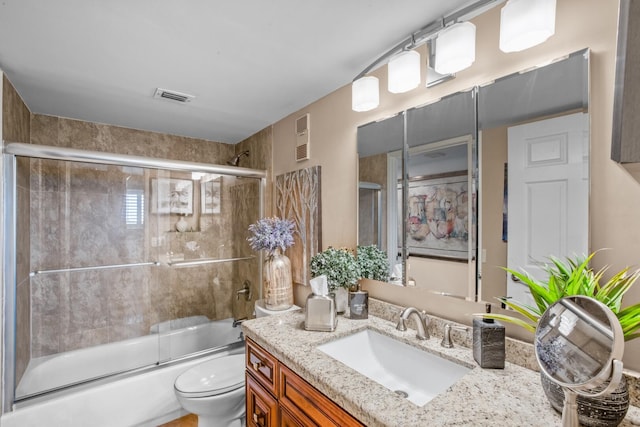 full bathroom featuring vanity, bath / shower combo with glass door, and toilet