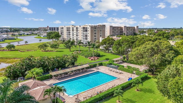 view of swimming pool with a patio area, a yard, and a water view