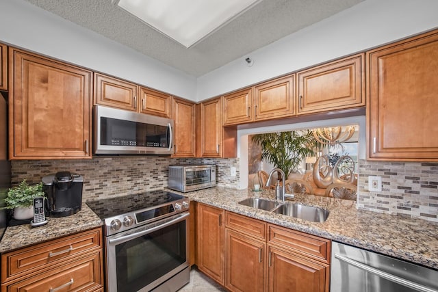 kitchen with light stone countertops, appliances with stainless steel finishes, sink, and decorative backsplash