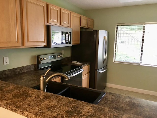 kitchen with light brown cabinetry, sink, tile patterned flooring, and appliances with stainless steel finishes