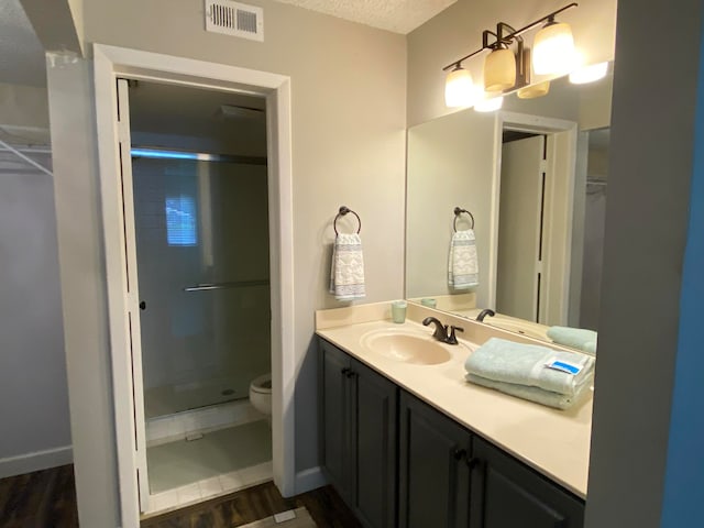 bathroom featuring hardwood / wood-style floors, vanity, toilet, and walk in shower