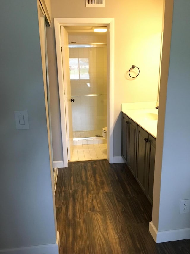 bathroom featuring hardwood / wood-style floors, vanity, toilet, and a shower with door