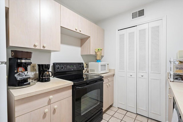 kitchen featuring black / electric stove, light brown cabinetry, and light tile patterned flooring