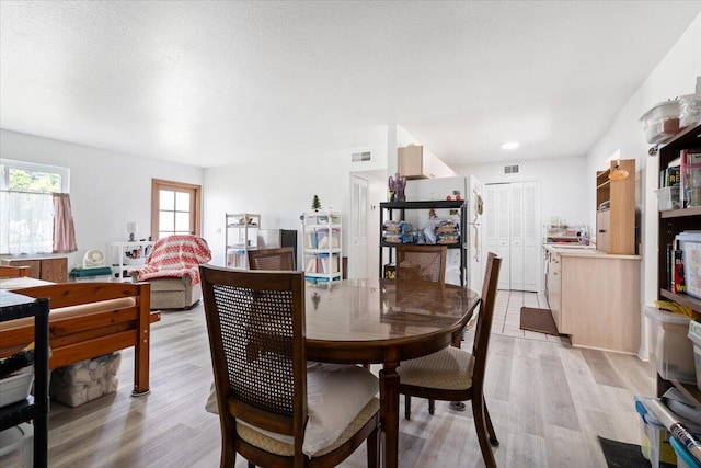 dining room with a textured ceiling and light wood-type flooring