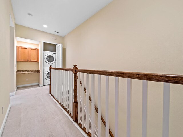 hall featuring stacked washer / dryer and light carpet