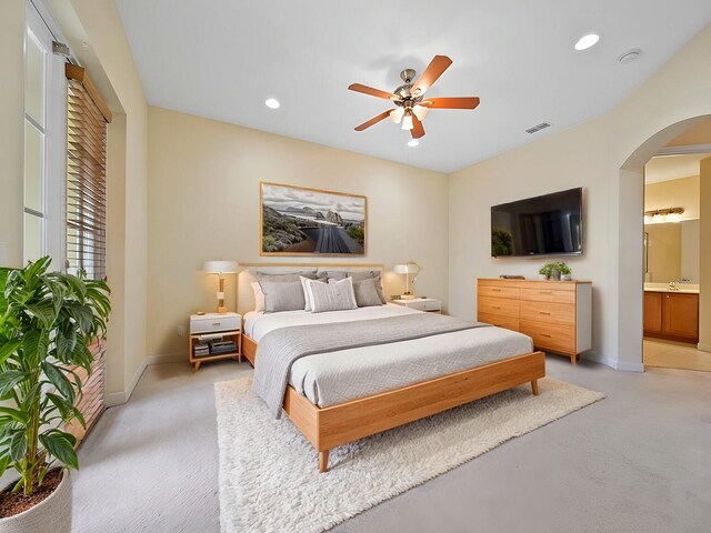 bedroom featuring light colored carpet, connected bathroom, and ceiling fan