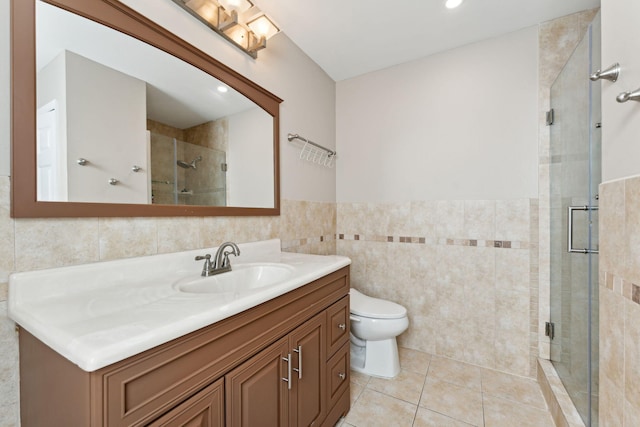 bathroom featuring tile patterned flooring, toilet, vanity, a shower with shower door, and tile walls