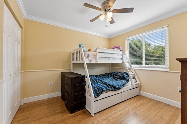 bedroom featuring light wood-type flooring, a closet, ceiling fan, and ornamental molding