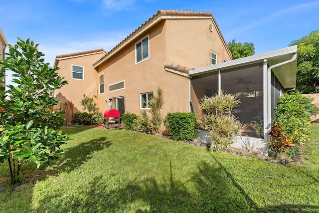 back of property with a sunroom and a yard