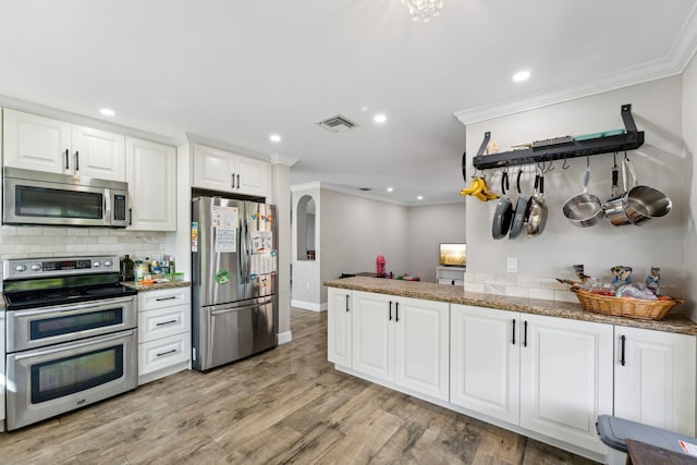 kitchen with light hardwood / wood-style flooring, ornamental molding, appliances with stainless steel finishes, stone countertops, and white cabinetry