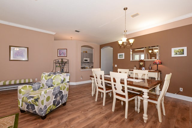 dining area with ornamental molding, dark wood-type flooring, and an inviting chandelier