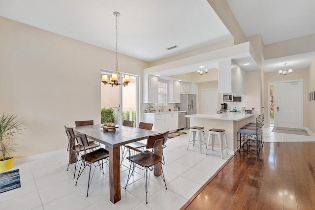 dining area with a chandelier, sink, and light hardwood / wood-style floors