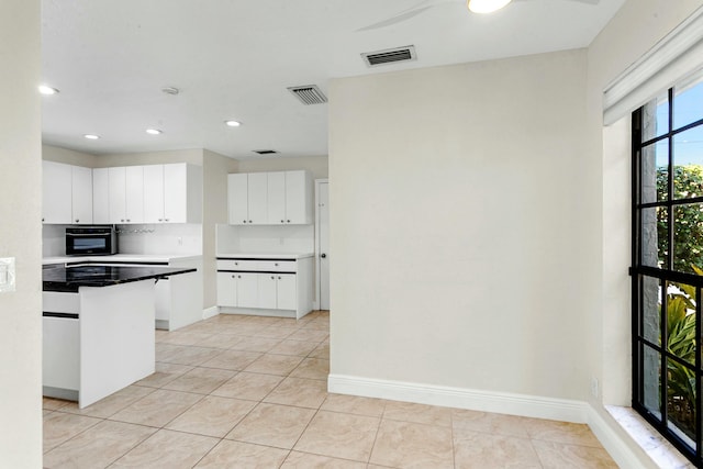 kitchen with oven, white cabinetry, and light tile patterned floors