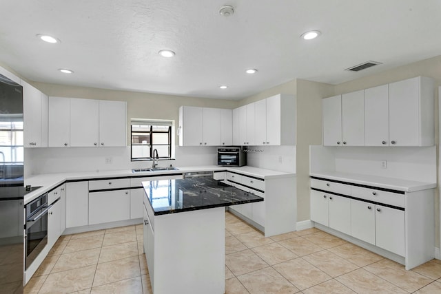 kitchen with light tile patterned floors, a center island, white cabinetry, and sink