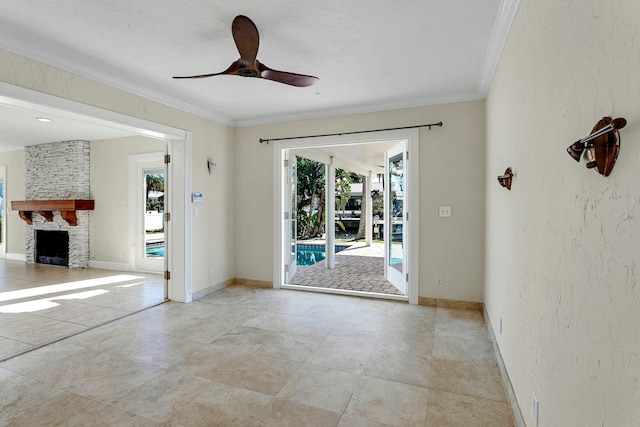 empty room featuring a wealth of natural light, a fireplace, ceiling fan, and ornamental molding