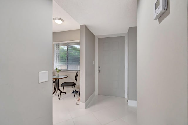 hall with a textured ceiling and light tile patterned floors