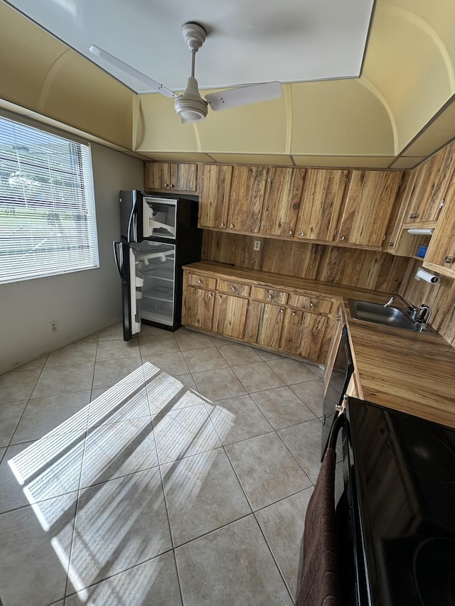 kitchen with ceiling fan, stove, light tile patterned floors, and sink