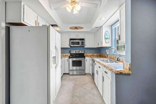 kitchen featuring white cabinets, stainless steel appliances, sink, and a raised ceiling