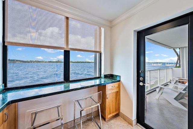 interior space with crown molding, light tile patterned floors, a water view, and a wealth of natural light