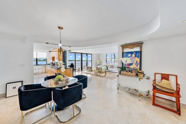 dining area featuring a chandelier, plenty of natural light, and a raised ceiling