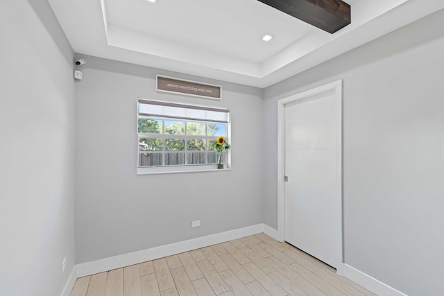 empty room with a tray ceiling and light hardwood / wood-style flooring