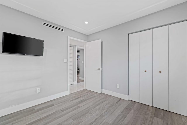 unfurnished bedroom with light hardwood / wood-style flooring and a closet