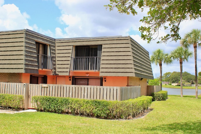 view of side of home featuring a lawn and a balcony