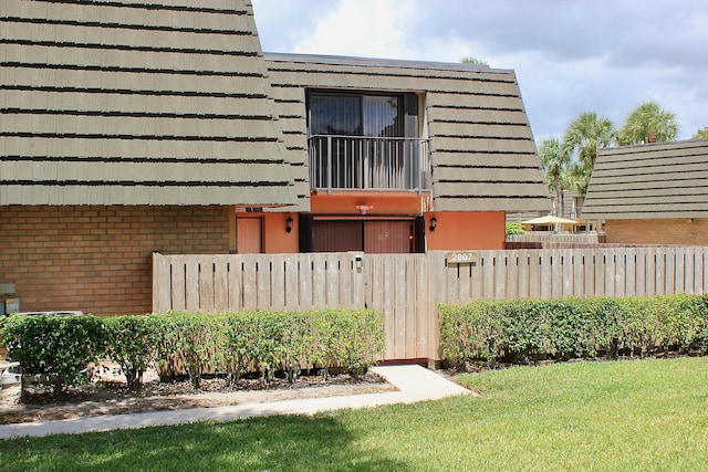 view of side of home with a lawn and a balcony