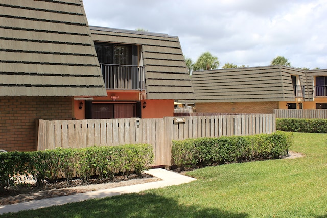 view of property exterior featuring a balcony and a lawn