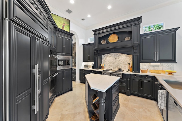 kitchen with backsplash, a center island, built in appliances, light tile patterned floors, and crown molding